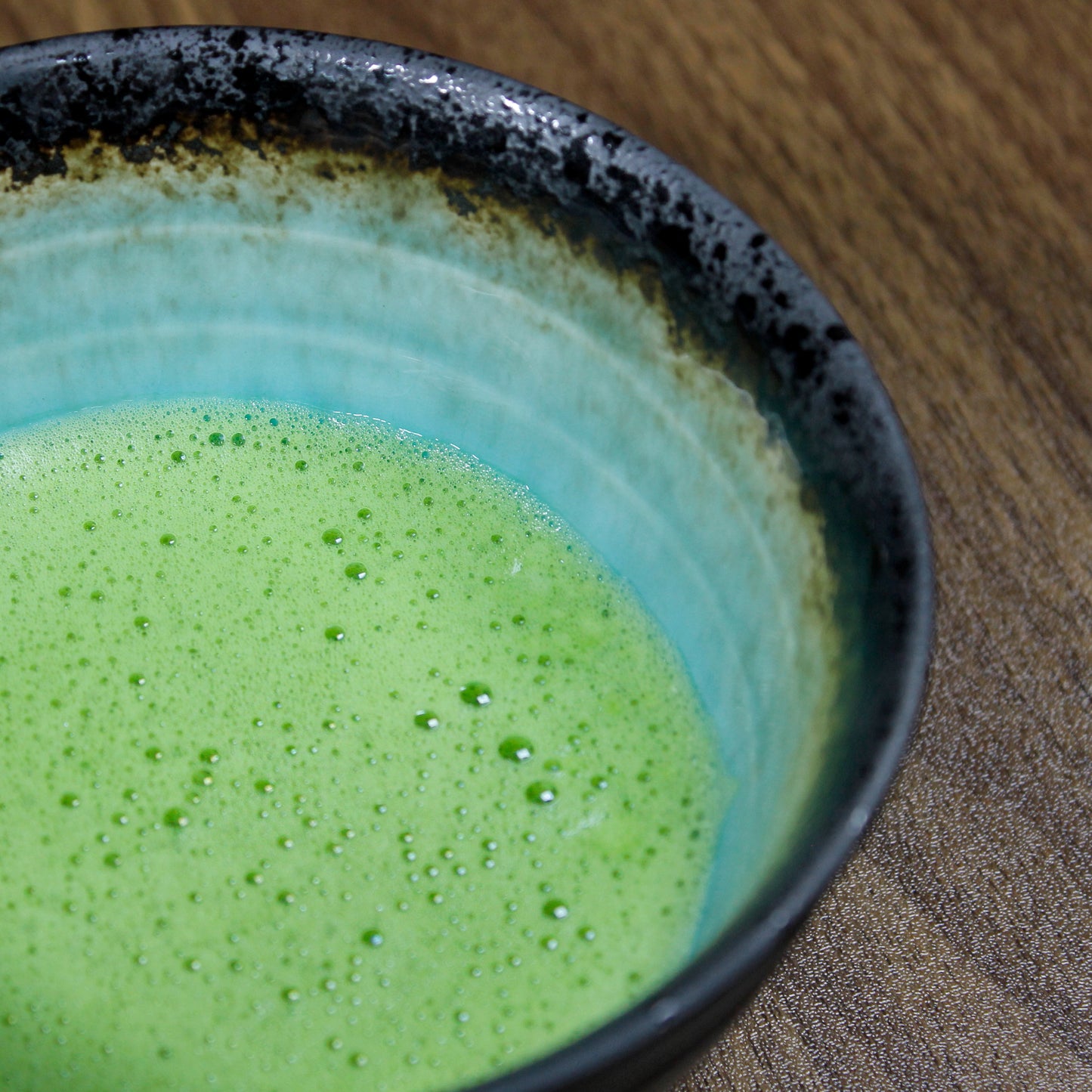 Gabaron Ceremonial Grade Matcha - Marukyu Koyamaen - Uji, Kyoto, Japan - whisked in a light blue black rimmed bowl on a dark wood surface. Tasting Notes:
nori • wheat grass • unsweetened cocoa