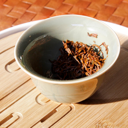 Wet leaves in a green gaiwan on a bamboo tray. 