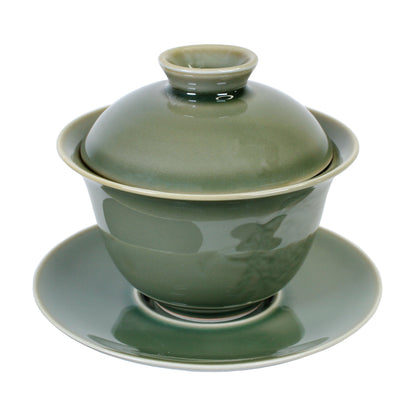Green ceramic gaiwan with lid and saucer on a white background