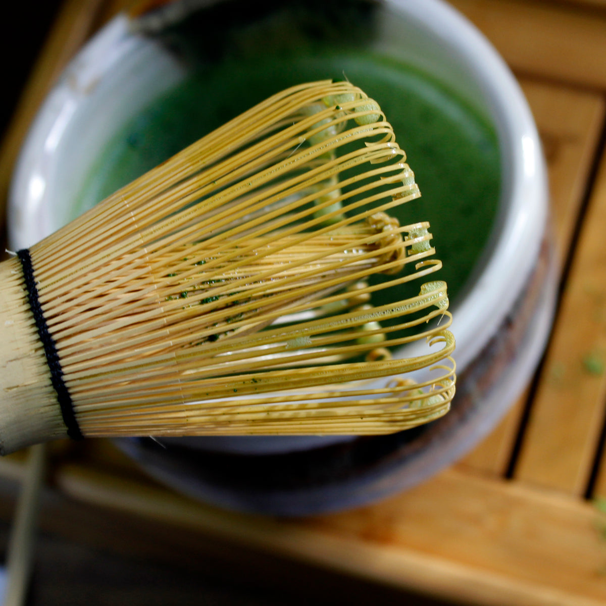 Bamboo Matcha Whisk - Chasen - used over a matcha bowl on a bamboo tray.