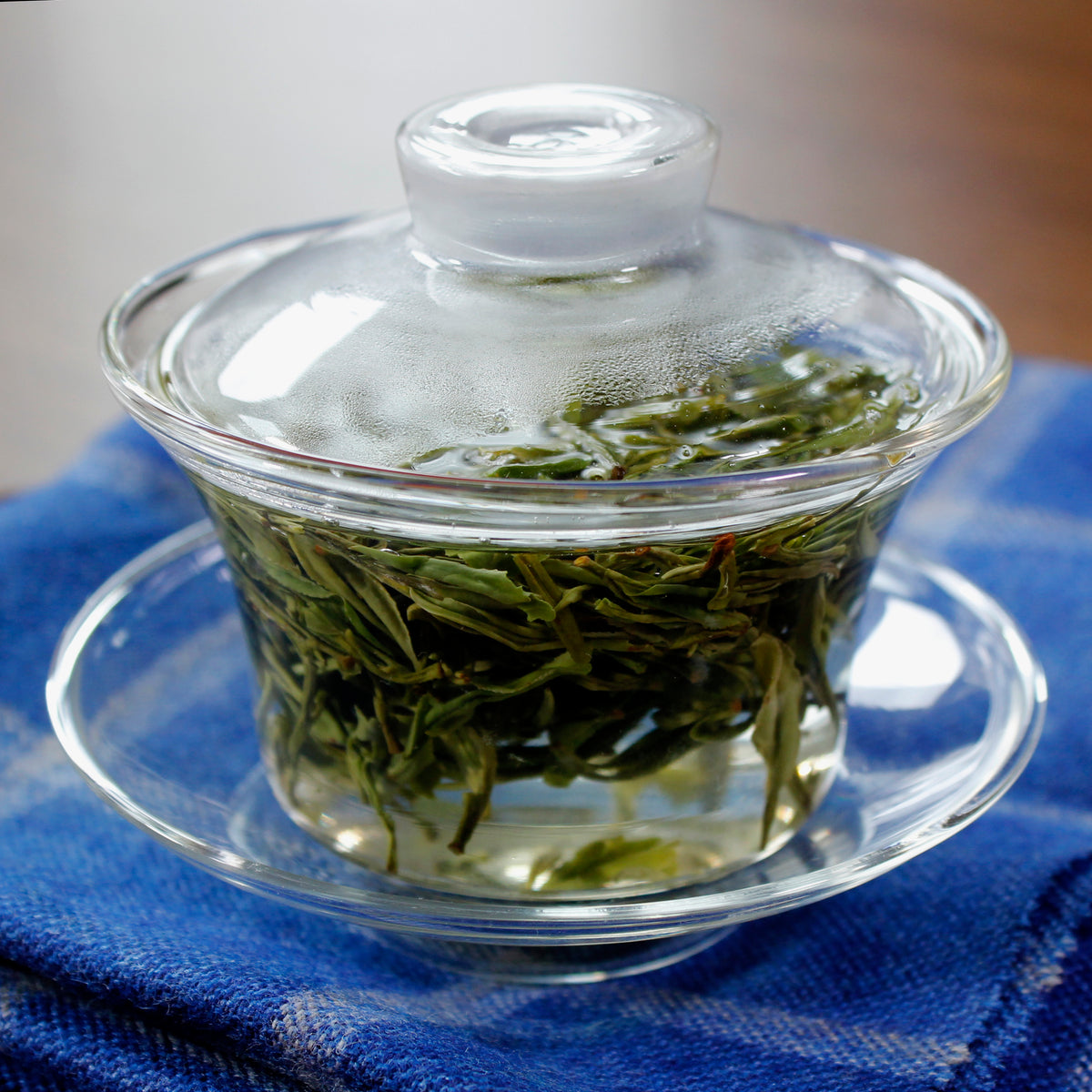 Glass cup with a lid and saucer, the inside is filled with tea and tea leaves