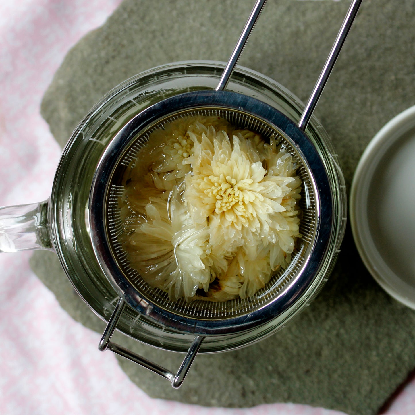 White flower tea brewing in the strainer on a piece of slate. 