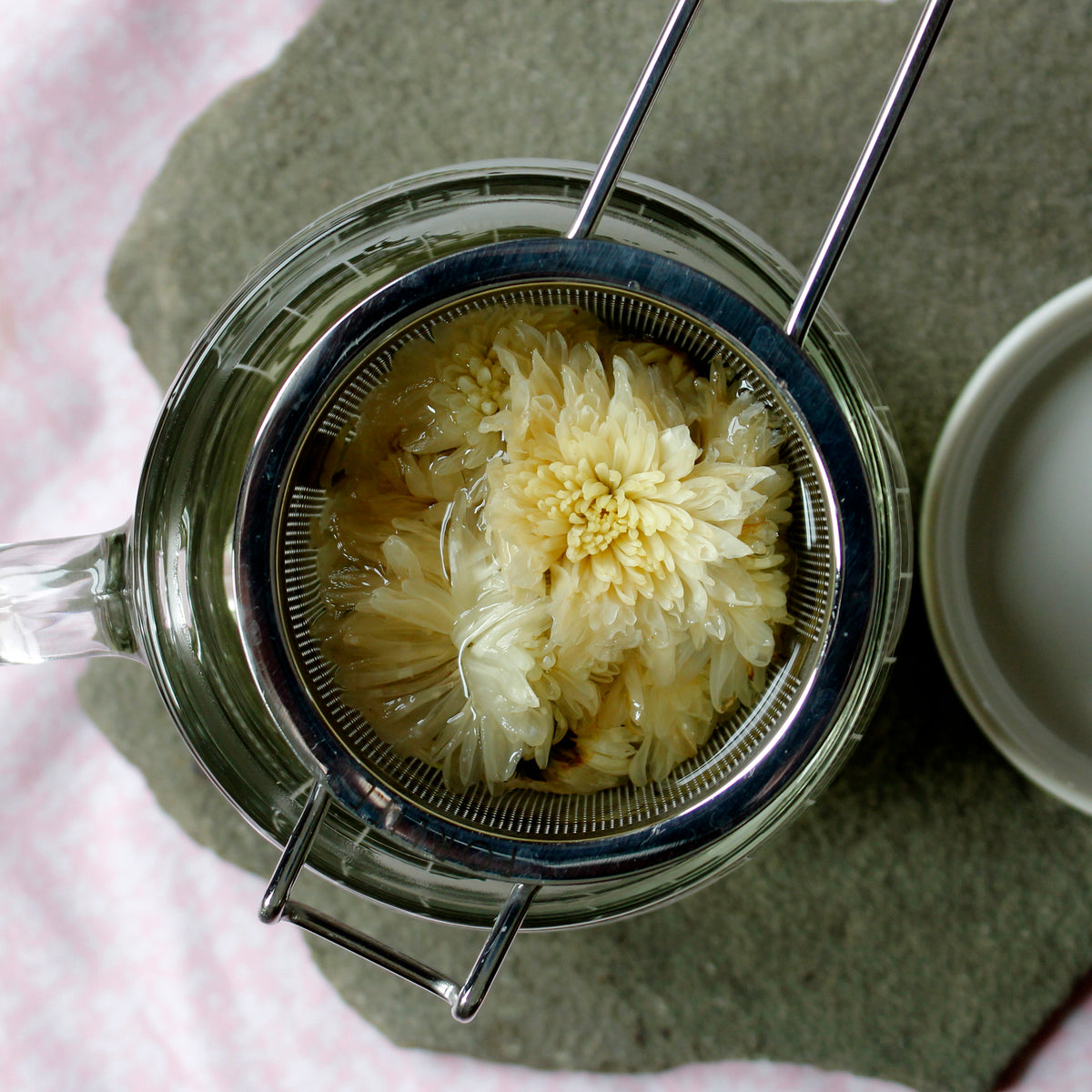 White flower tea brewing in the strainer on a piece of slate. 